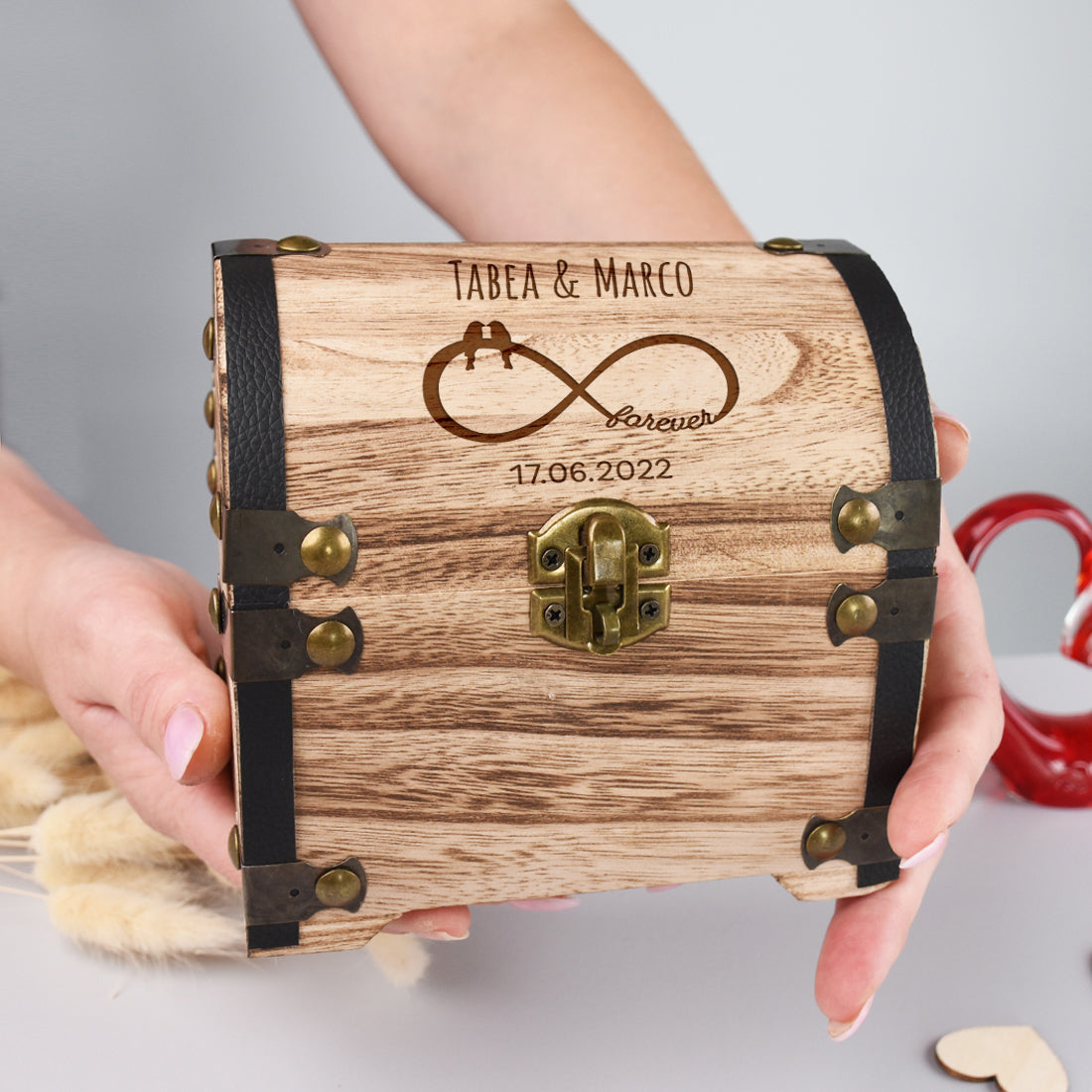 Personalisierte Schatztruhe aus Holz zur Hochzeit in den Händen gehalten
