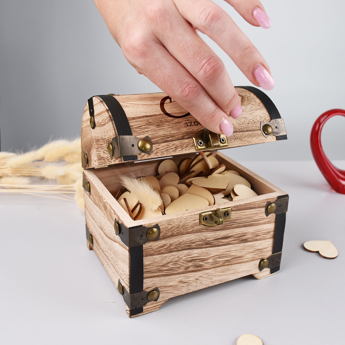 Geöffnete Holz-Schatztruhe mit personalisierter Gravur und Hochzeitsdeko, von Hand geöffnet
