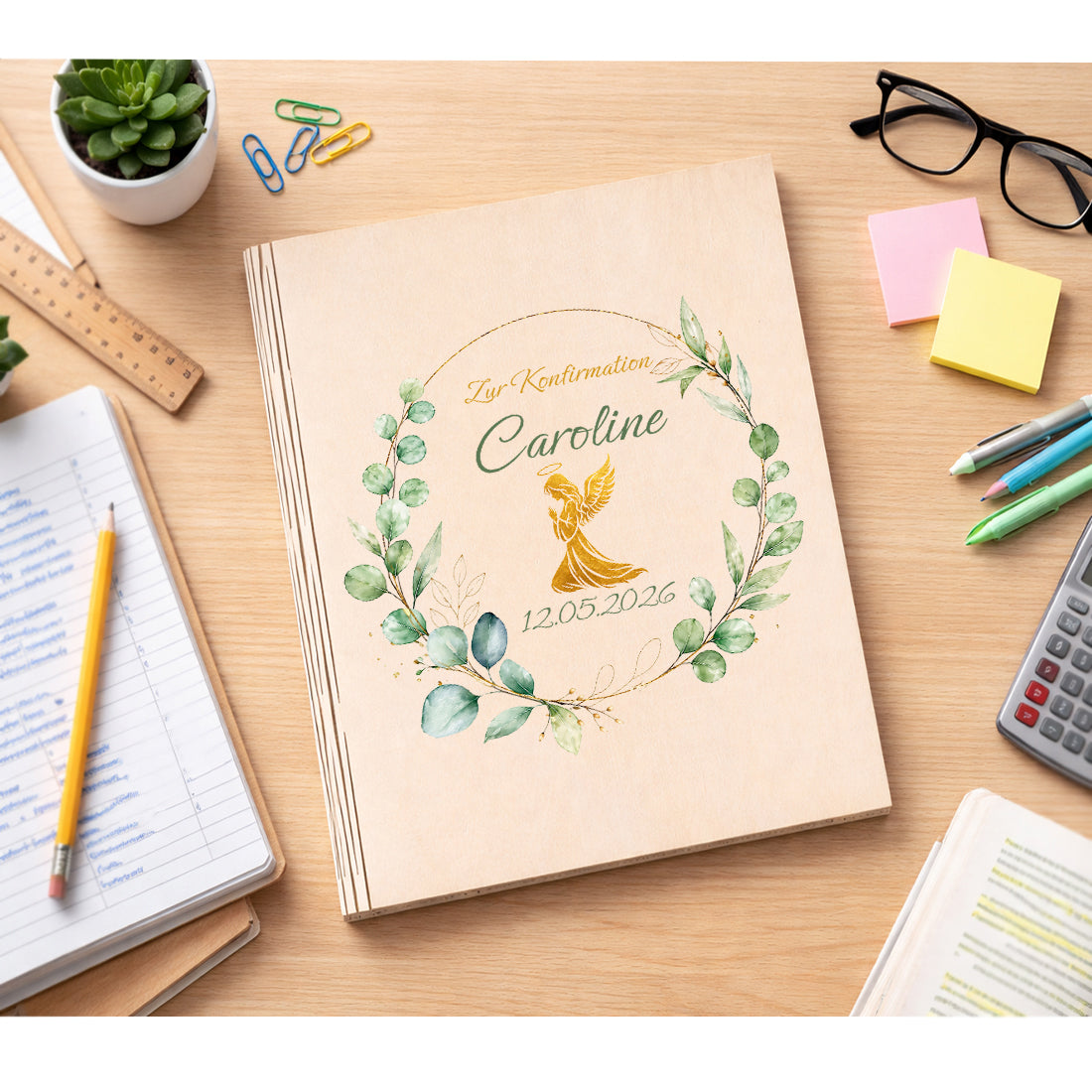 Gästebuch aus Holz mit goldener Taube und Eukalyptuskranz neben Schreibutensilien