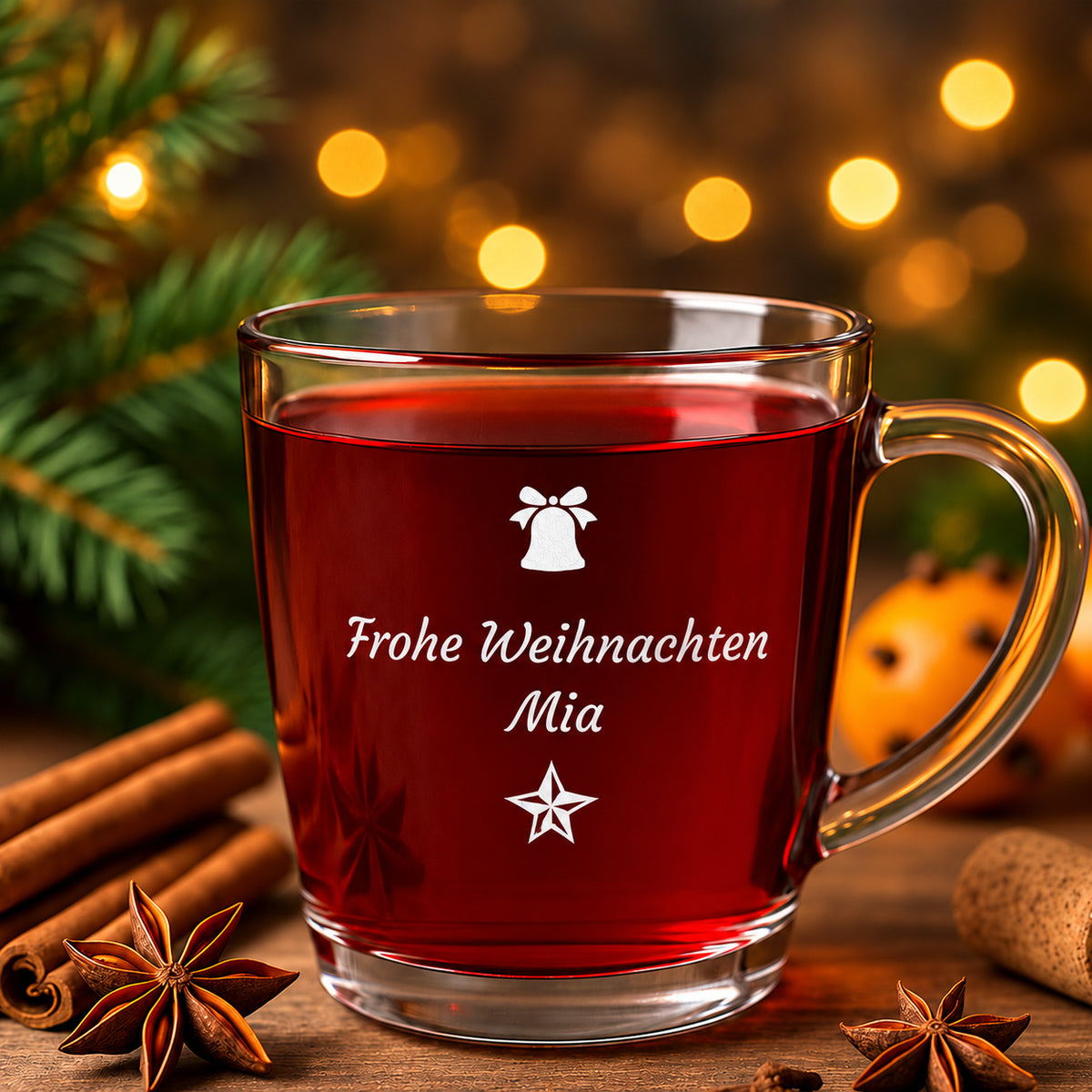 Glühweinglas mit Glocke, Stern und Beispieltext Frohe Weihnachten Mia auf einem weihnachtlichen Tisch