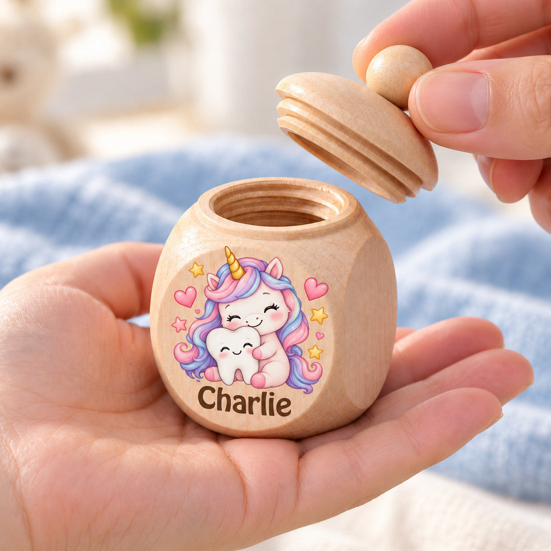 Zahndose mit Motiv Einhorn & Zahn in einer Hand als Größenvergleich