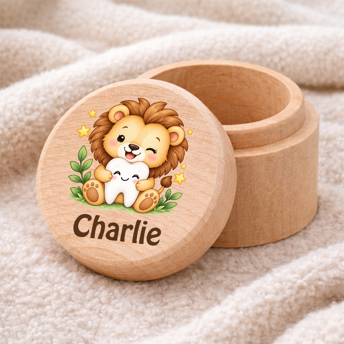 Runde Zahndose mit Motiv Löwe & Zahn und Beispielname Charlie auf einer weichen Decke