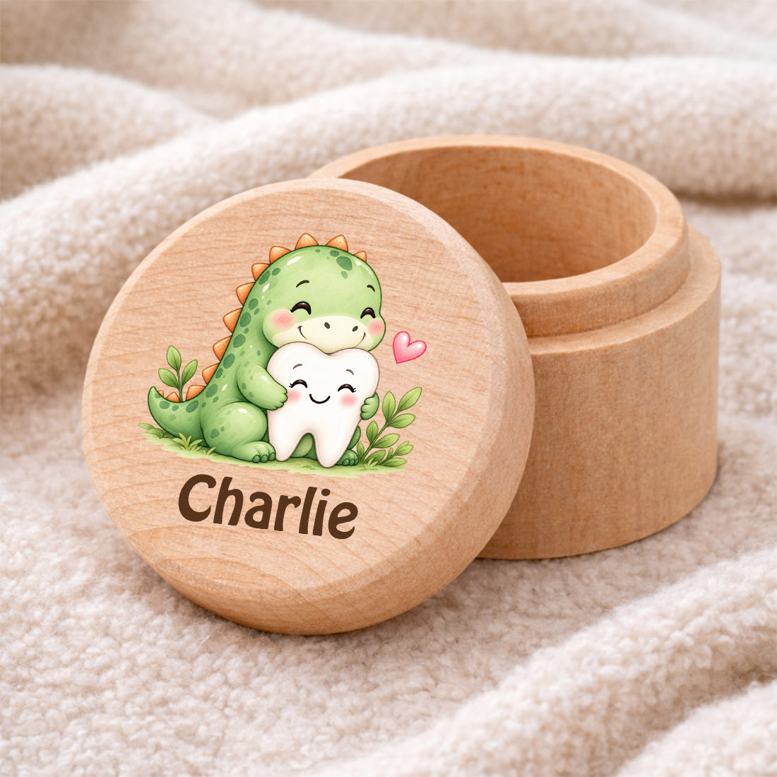 Runde Zahndose mit Motiv Dino & Zahn und Beispielname Charlie auf einer weichen Decke