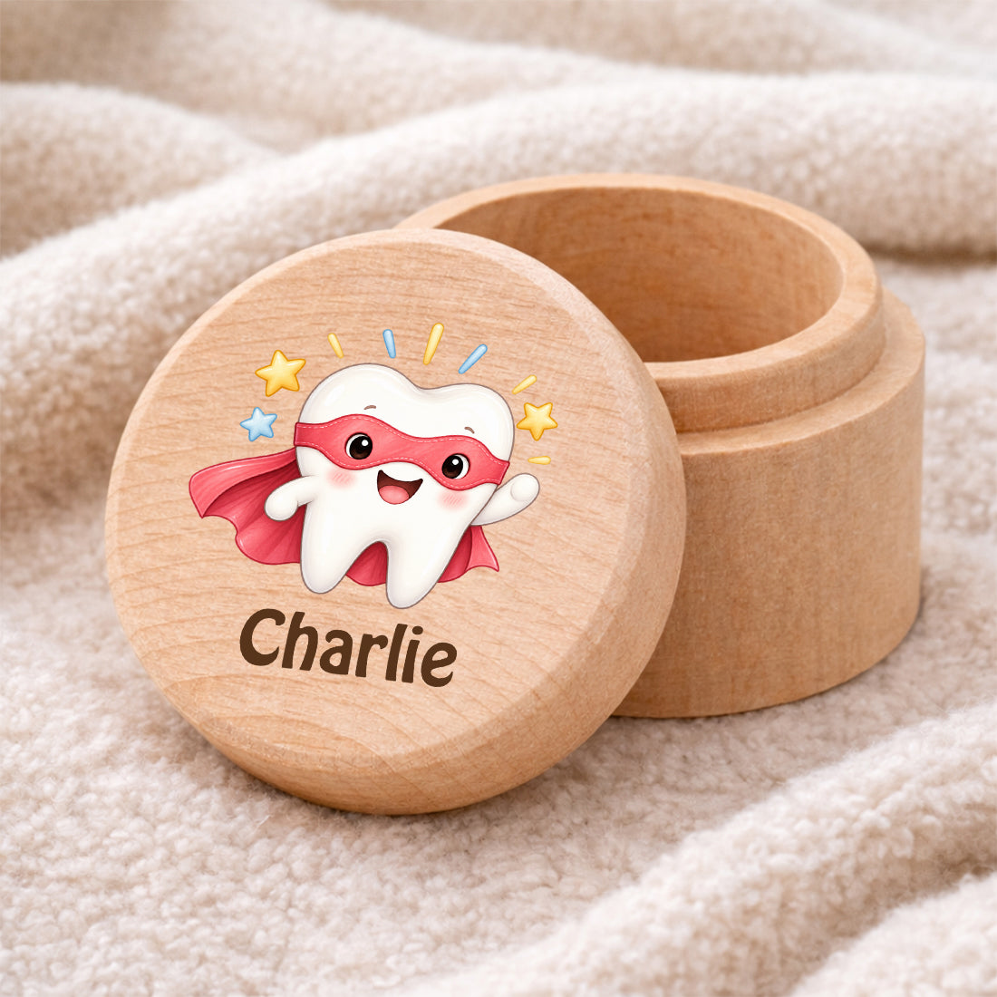 Runde Zahndose mit Motiv Superzahn und Beispielname Charlie auf einer weichen Decke