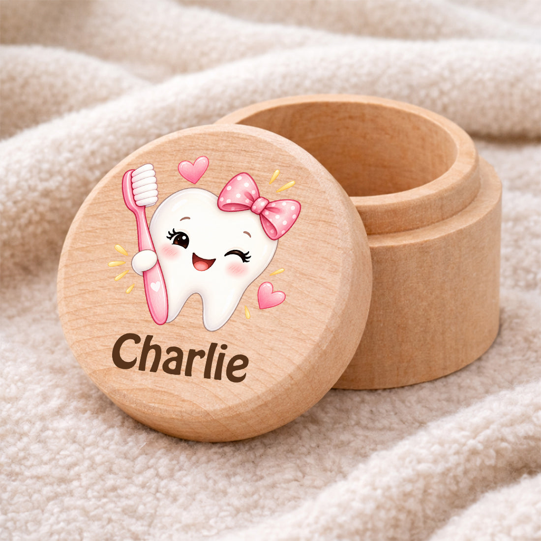 Runde Zahndose mit Motiv Zahn & Zahnbürste und Beispielname Charlie auf einer weichen Decke