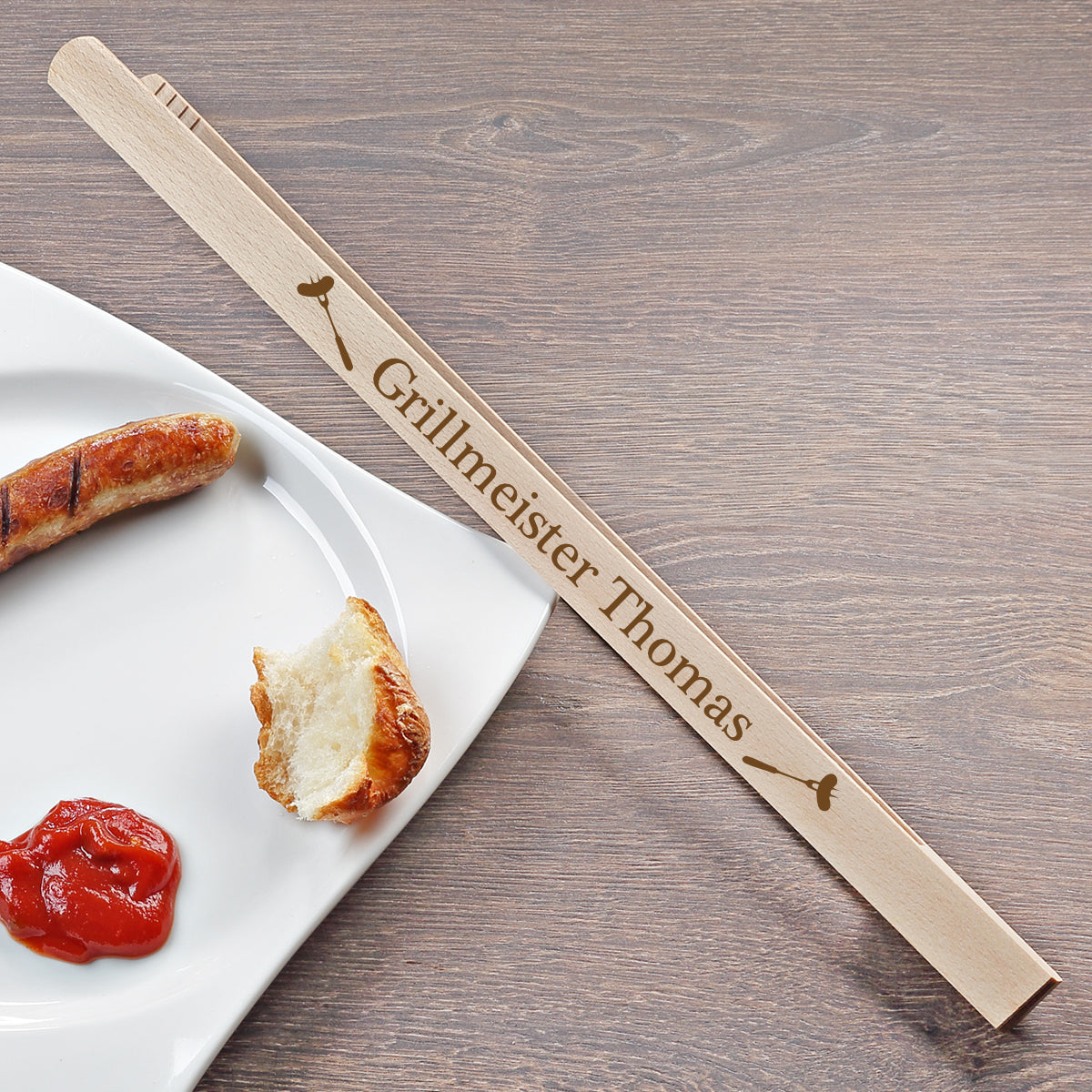 Personalisierte Grillzange als Geschenk auf weißem Teller mit Dekoration
