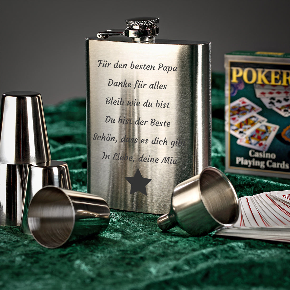 Flachmann mit Wunschgravur und Stern-Motiv neben Spielkarten auf einem Pokertisch