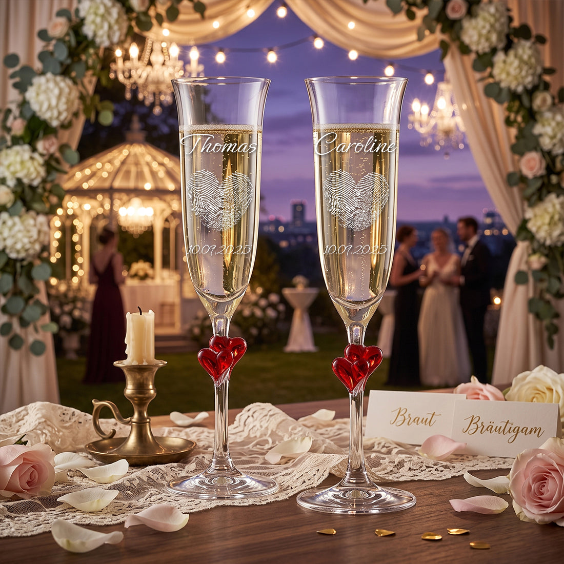 Sektgläser mit rotem Herz-Stiel und Namen auf festlich geschmücktem Hochzeitstisch mit Blumen und Pavillon.