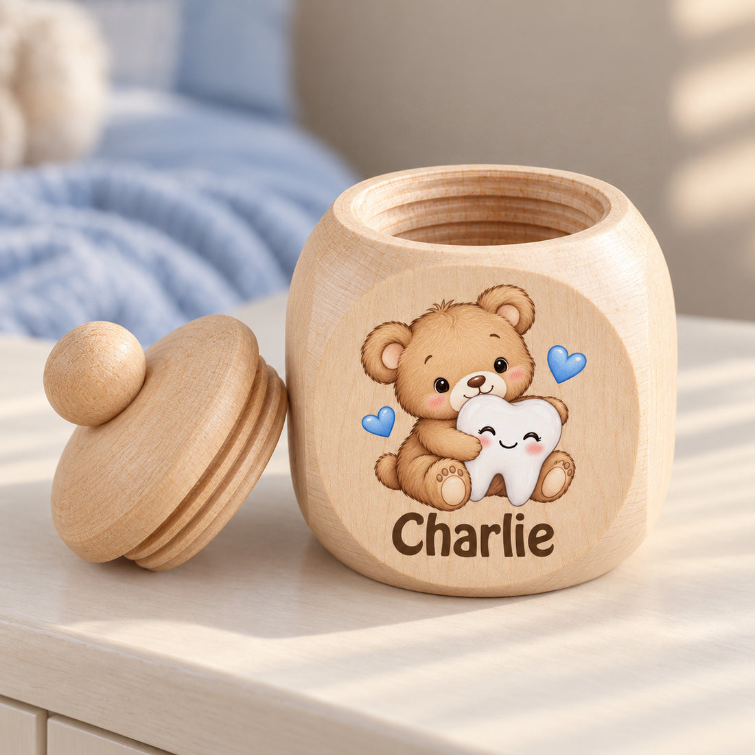 Geöffnete Zahndose mit Motiv Teddybär & Zahn, Schraubdeckel daneben im Kinderzimmer
