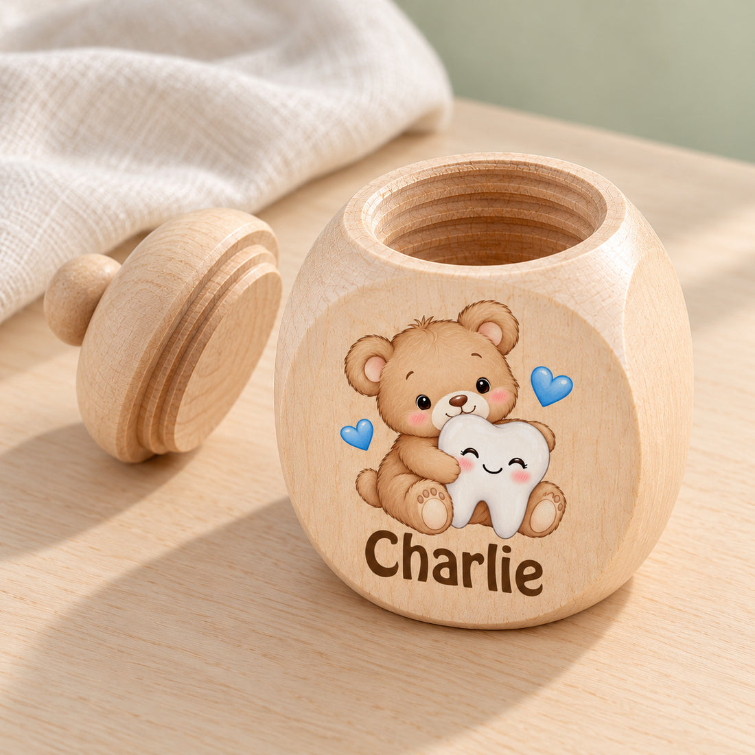Geöffnete Zahndose mit Motiv Teddybär & Zahn von oben und Schraubdeckel daneben
