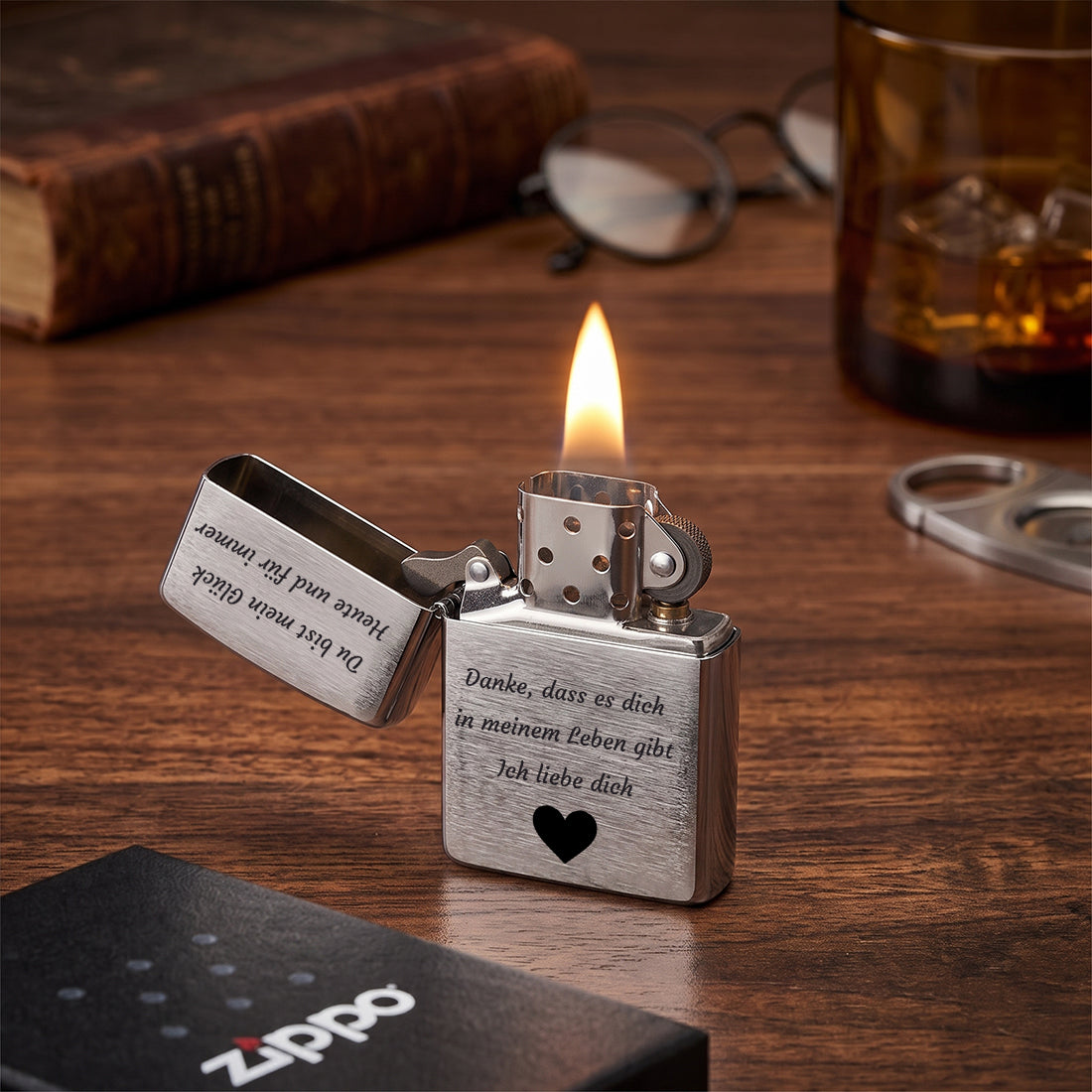 An gezündetes Zippo Feuerzeug mit Gravur auf Holzoberfläche neben Whiskyglas